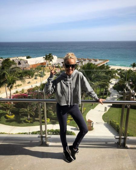 Kristin Chenoweth in a grey hoodie poses for a picture in front of a ocean.
